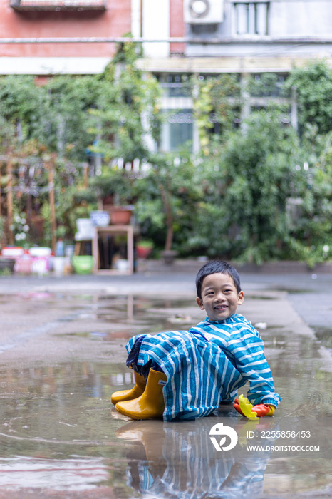 快乐的小男孩雨后在水坑玩耍