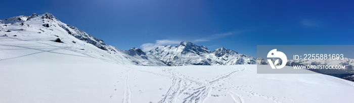 view on peak mountain covered with snow and ski tracts under blue sky in Alps