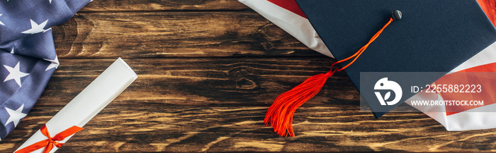 horizontal crop of graduation cap and diploma near american flag with stars and stripes on wooden surface