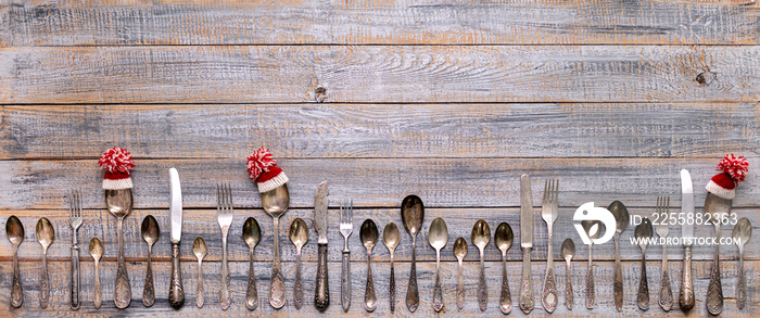 Merry Christmas! Vintage cutlery in santa claus hats on old wooden background.
