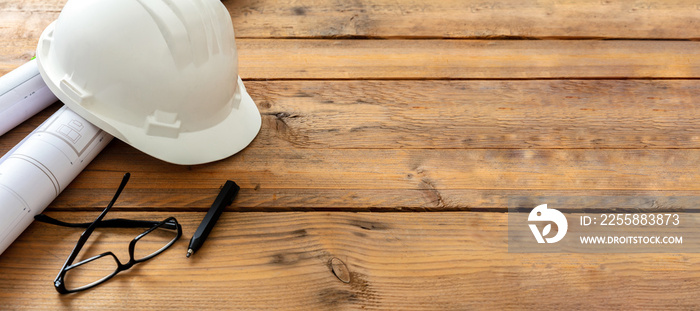 Construction safety concept. Building drawings and engineer white helmet on a wooden table, space