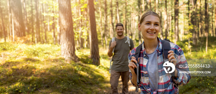 young travel couple with backpacks on nature adventure hike in forest. banner with copy space