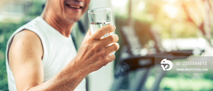 Senior man drink mineral water in gym fitness center after exercise. Elderly healthy lifestyle.