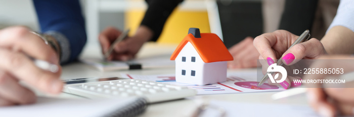 Group of people discussing chart on documents near toy house closeup