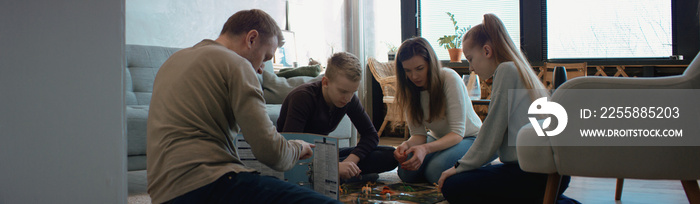 Family - father, mother and two kids playing a board game together. Stay home, quarantine. Board game is custom made for the shot