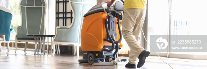 Janitor is cleaning hall with washing vacuum cleaner closeup