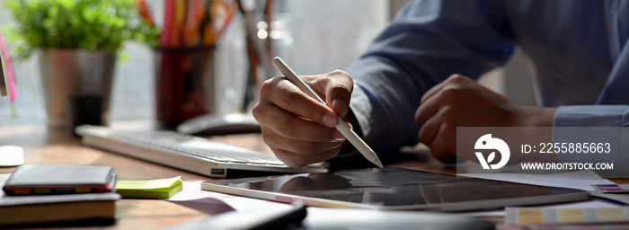 Close up view of graphic designer drawing on digital tablet on wooden worktable