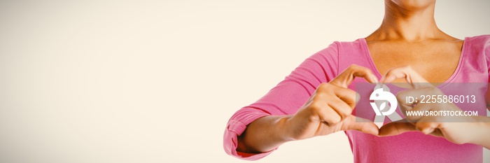 Women wearing pink shirt making heart with their fingers around