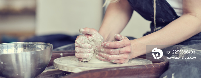 Close up banner, female hands make dishes from clay. woman hands working on potters wheel. The master potter works in a workshop