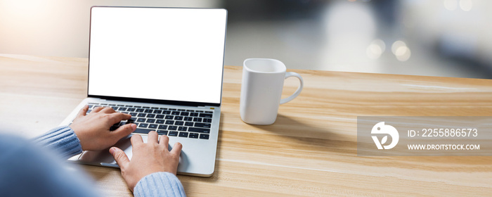 close up hand of woman working and typing on laptop computer on wood table, white screen notebook for present project and products with copy space table