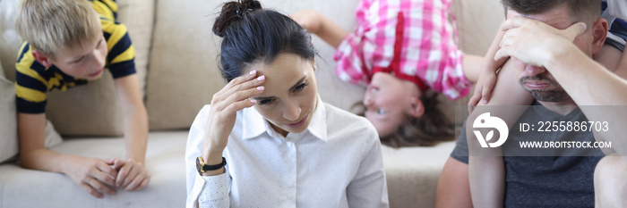 Tired man and woman are sitting on floor with laptop holding their heads with their hand behind them on couch children indulge. Fatigue and depression in families concept