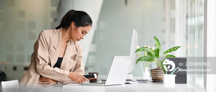 Attractive female designer holding her mobile phone in creativity office.