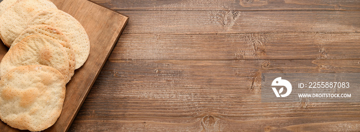 Board with Jewish flatbread matza for Passover on wooden background with space for text