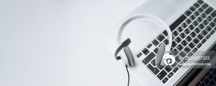 Top view of laptop, white headphones with microphone on table, empty place for text.