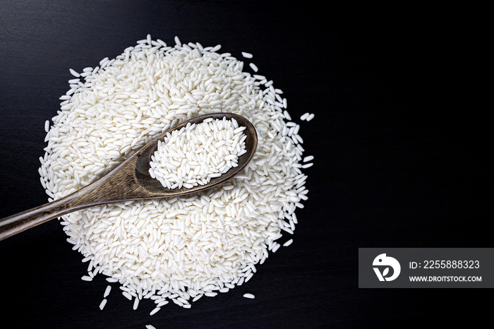 Glutinous rice in a wooden spoon Resting on glutinous rice On a black wooden table. Top view.