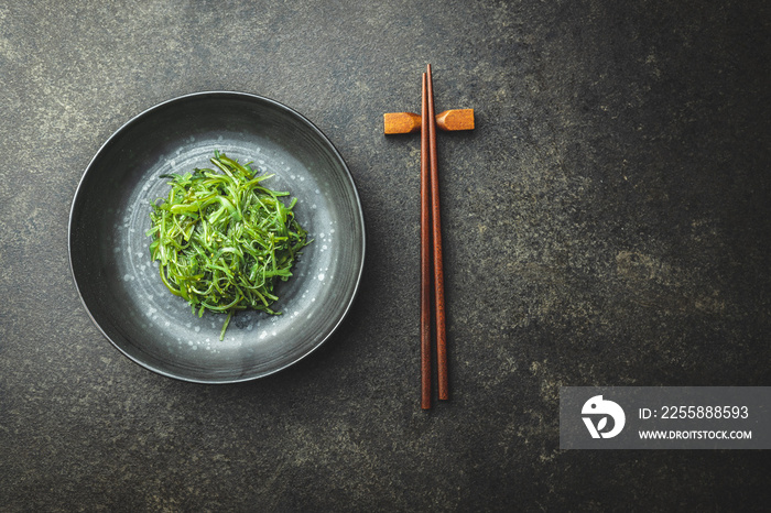 Green wakame. Seaweed salad in bowl on black table.