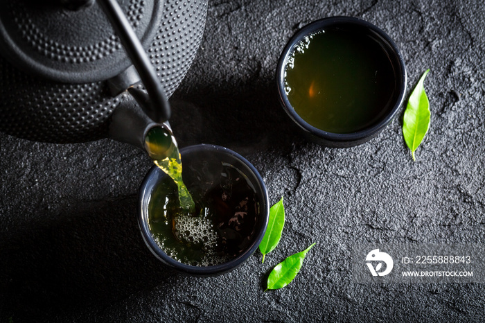 Delicious green tea with teapot and cup on black rock