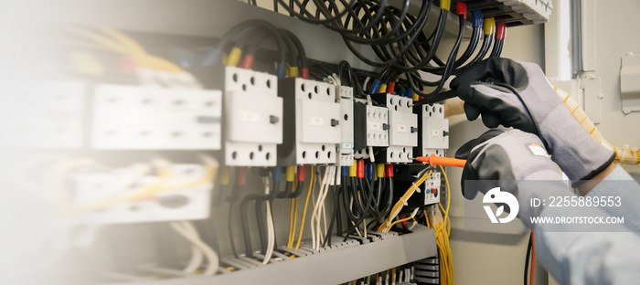 Electrical engineers test electrical installations and wiring on protective relays, measuring them with a multimeter.