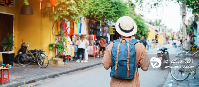 happy Solo traveler sightseeing at Hoi An ancient town in central Vietnam, man traveling with backpack and hat. landmark and popular for tourist attractions. Vietnam and Southeast Asia travel concept