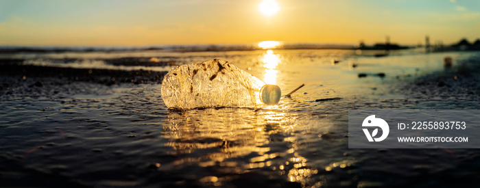 Plastic bottle on sea shore, stone ground show long life garbage concept.