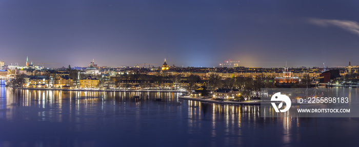 En vacker utsikt över Skeppsholmen med Konstfack och Kastellholmen med det gamla röda Kastellet. Gatubelysning glittrar och reflekteras i vattnet denna vackra vinternatt .