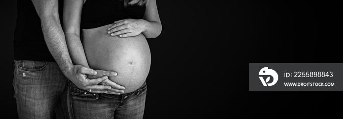 pregnant belly couple holding hands around baby bump black background