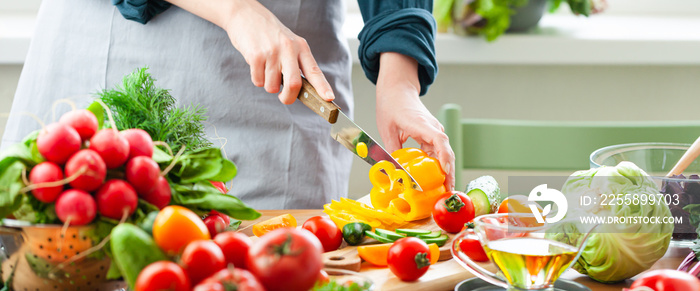 Beautiful young woman slicing yellow pepper, preparing delicious fresh vitamin salad. Concept of clean eating, healthy food, low calories meal, dieting, self caring lifestyle. Close up