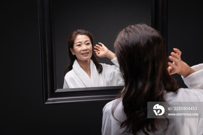 照镜子捋头发的优雅中年女人