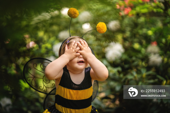 Baby girl in costume of bee covering her eyes with hands . Funny expression. Copy space