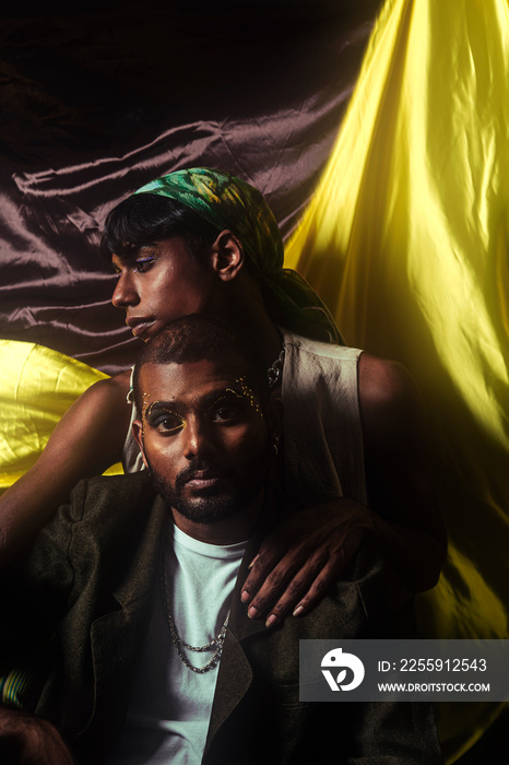 Two Malaysian Indian men in a studio setting with cloth flying in the background, posing against a b