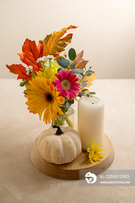 Autumn flowers and pumpkin. Bouquet of fresh flowers, candle and decorative pumpkins warm neutral ba