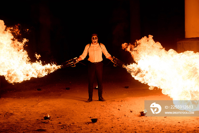 Halloween man in costume with flamethrower in his hands. Devil makeup on face