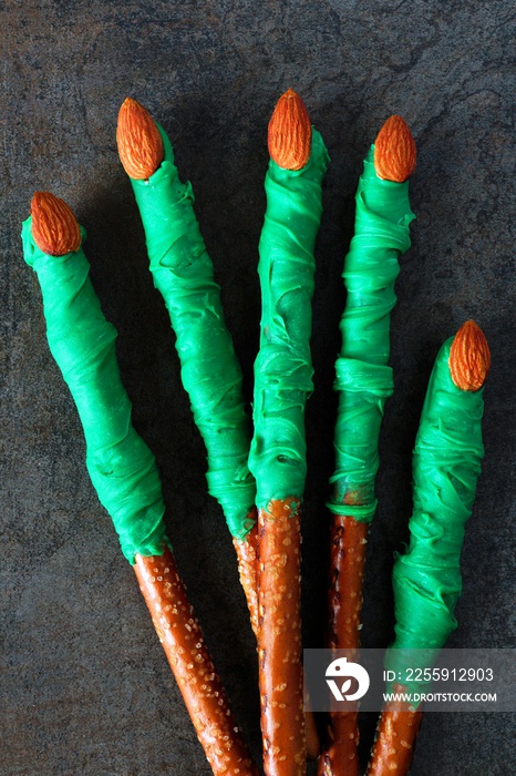 Group of Halloween witches finger, candy dipped pretzel rods on black stone background