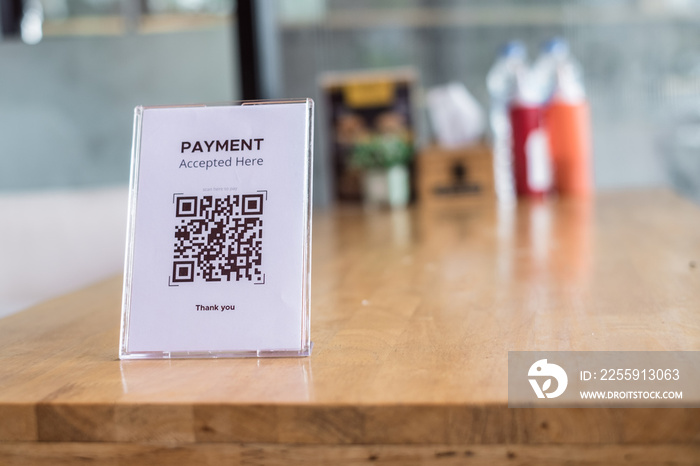 QR code payment accepted in acrylic or plexiglass table card holder on wooden table for restaurant. 