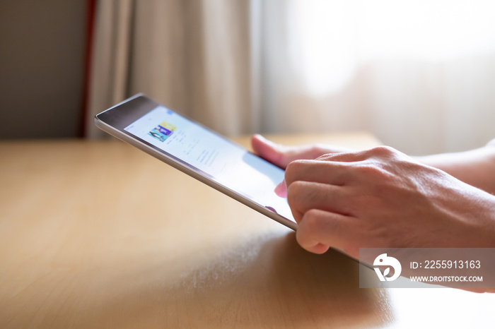 Selective focus at the edge of tablet. Men hand pressing the screen of smartphone tablet while searc