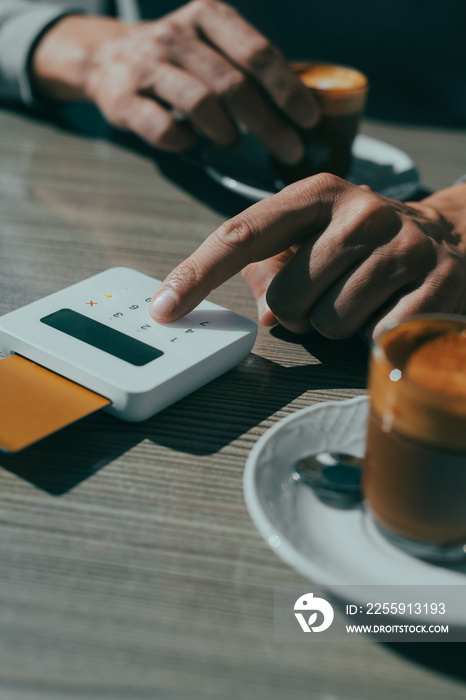 man inserts the PIN of his credit card in a cafe