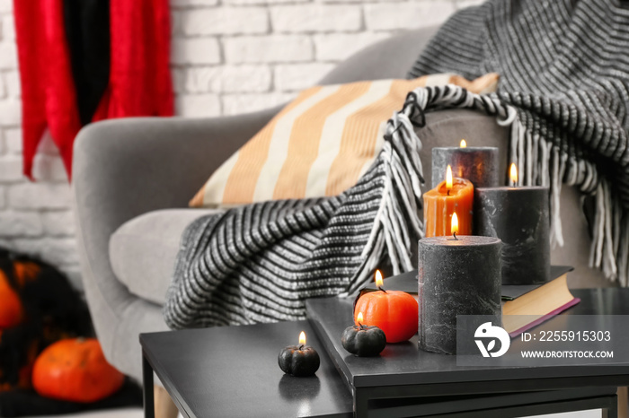 Table with burning candles prepared for Halloween celebration in room