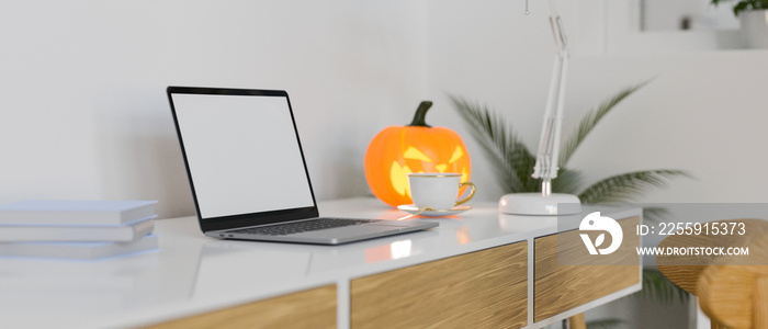 Side view of modern workspace with laptop, supplies and halloween decorations