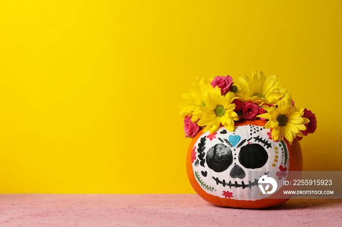 Pumpkin with catrina skull makeup and flowers on yellow background