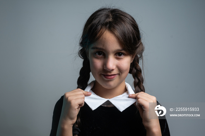 Portrait of little girl with Wednesday Addams costume during Halloween. Serious expression and dark 