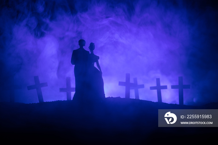 Halloween. Scary zombie bride on a night cemetery holds a pumpkin lantern.