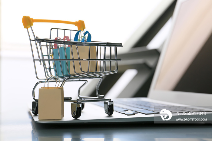 Small cart and laptop on table. Internet shopping concept