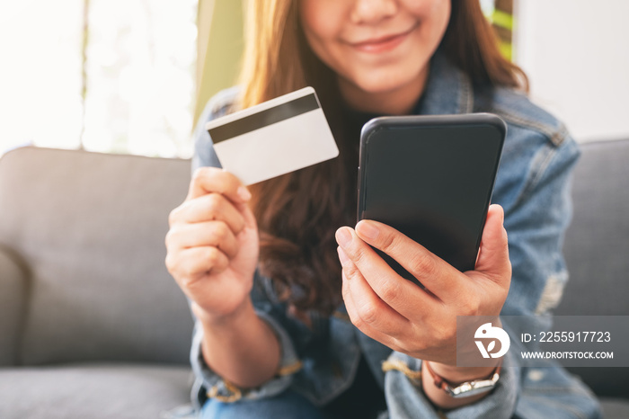 An asian woman using credit card for purchasing and shopping online on mobile phone