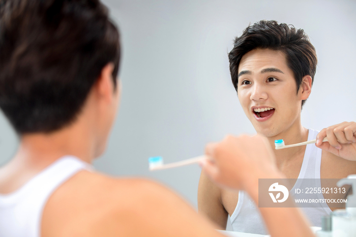 年轻男人对着镜子在刷牙