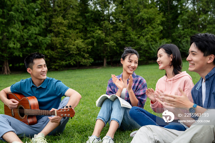 快乐的大学生在草地上弹吉他唱歌