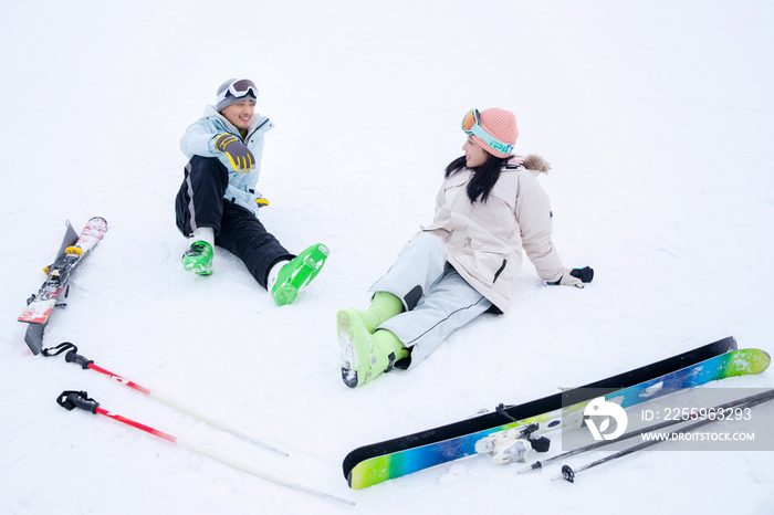 快乐的青年伴侣坐在雪地上闲聊