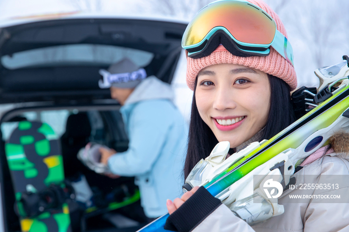 汽车后的青年伴侣拿着滑雪板