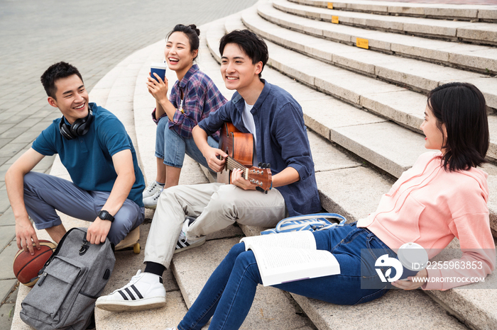 年轻的大学生坐在台阶上弹吉他