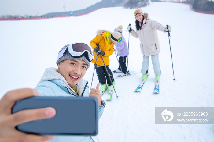 滑雪场上用手机自拍的一家四口
