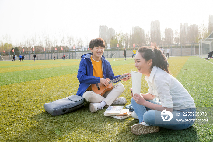 青年大学生在校园里弹奏吉他